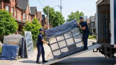 movers loading furniture into a moving truck in a Toronto residential area with CN Tower view.