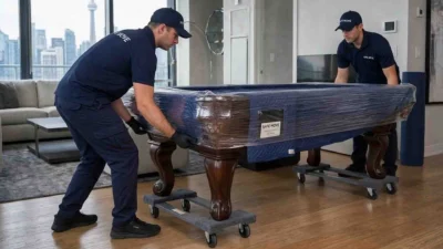 pool table movers in Toronto wrapping and transporting a billiard table.